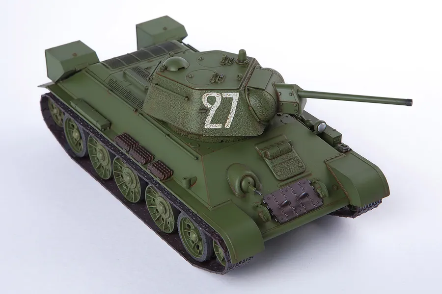 A high-angle studio shot of a 1/35 scale Academy USSR T-34/76 tank model kit, painted in olive green with the number 27 on the turret.