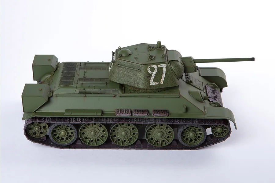 A side view of a 1/35 scale Academy T-34/76 tank model kit, painted olive green with the number 27 on the turret.