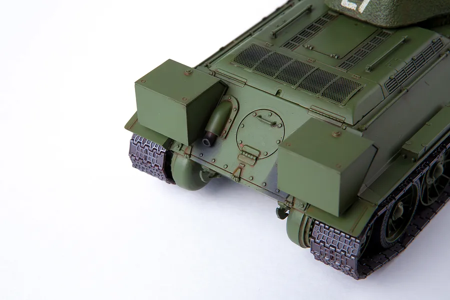 Rear view of an assembled and painted olive green T-34/76 tank model kit on a white background.
