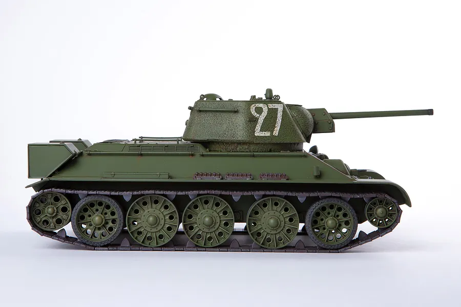 A side-profile view of an assembled and painted 1/35 scale T-34/76 tank model, featuring olive green paint and the number 27 on the turret.