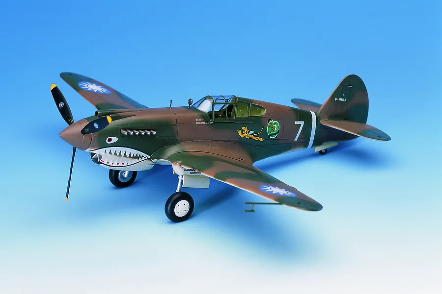 A fully assembled and painted 1/48 scale model of a P-40C Warhawk Flying Tigers fighter plane, featuring shark mouth nose art and camouflage paint.