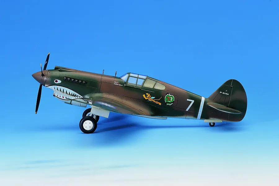 A side-profile view of a completed 1/48 scale plastic model of a P-40C Warhawk Flying Tigers fighter plane, featuring shark mouth nose art.