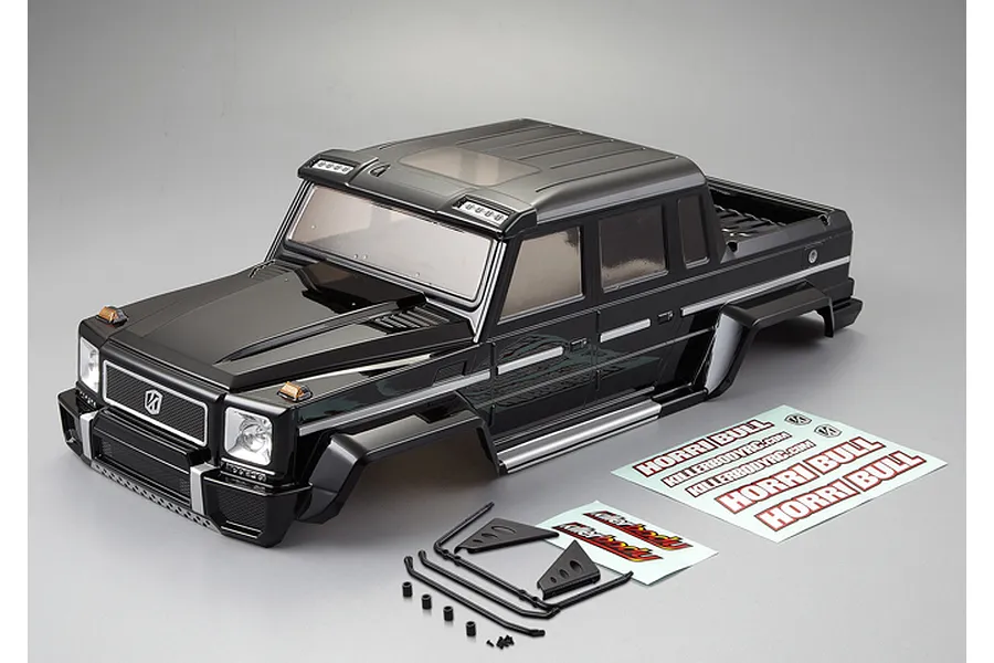 A black painted 1/10 scale Killerbody Horri-Bull RC crawler body shell with included decal sheets and small plastic accessory parts on a grey background.