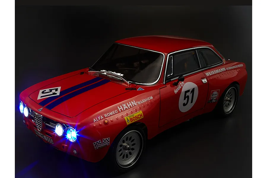 A red Killerbody 1/10 scale Alfa Romeo 2000 GTAm RC car body shell with racing decals and illuminated LED headlights against a black background.