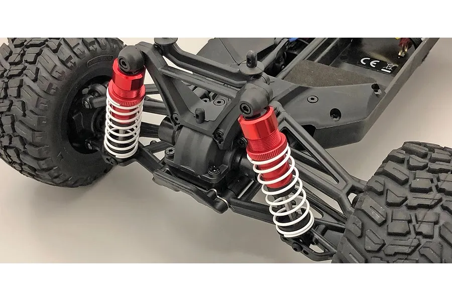 Close-up of red aluminium shock absorbers installed on a black RC car chassis with white springs.