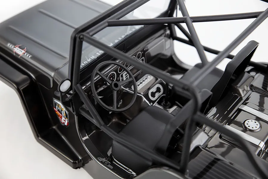 High-angle view of the interior of a grey RC crawler body shell featuring a roll cage, steering wheel, and dashboard details.