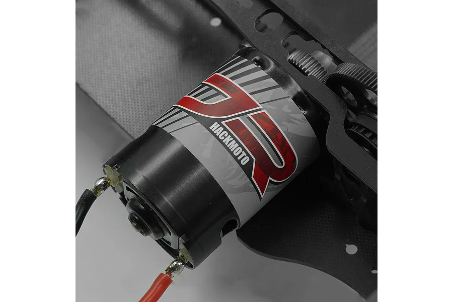 A Yeah Racing Hackmoto Just-Race brushed 540 motor installed on a carbon fiber RC chassis, showing the branded label and soldered wires.