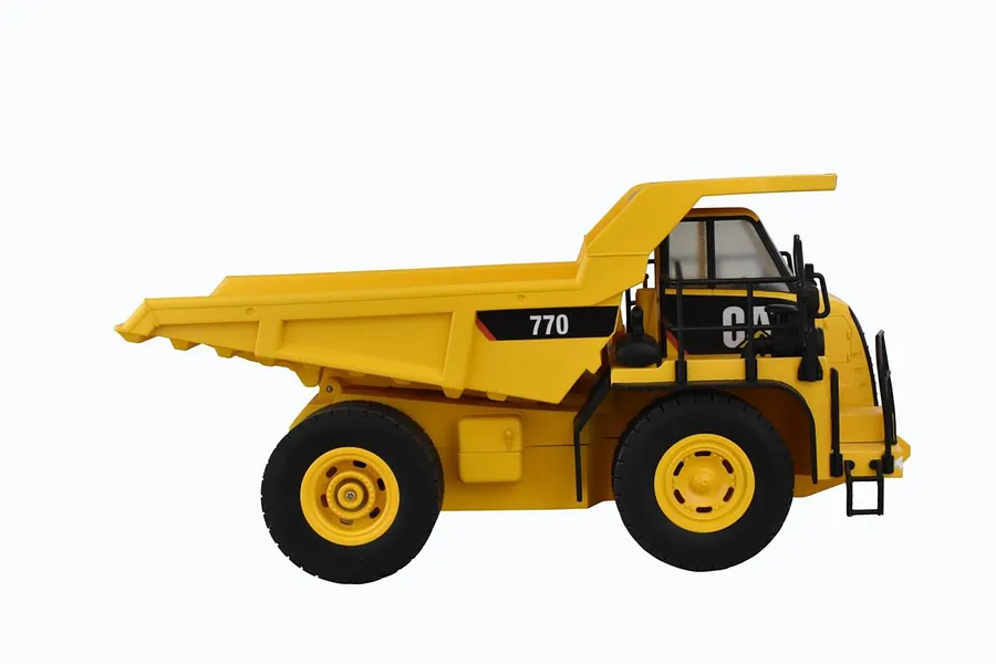 Side view of a yellow Diecast Masters CAT 770 RC mining truck on a white background.
