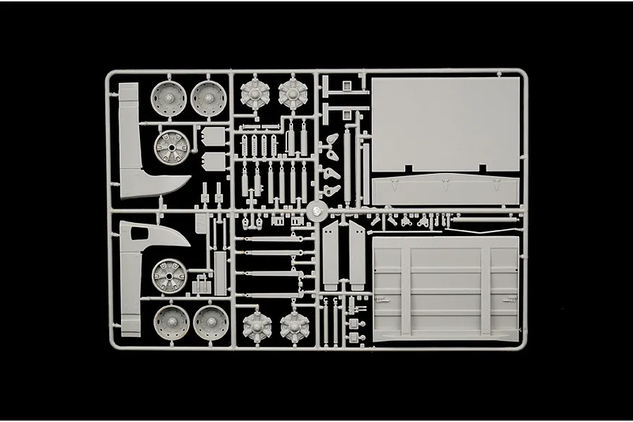 A grey plastic sprue from an Italeri 1/24 scale model kit containing various truck parts like wheels, suspension components, and flat panels.