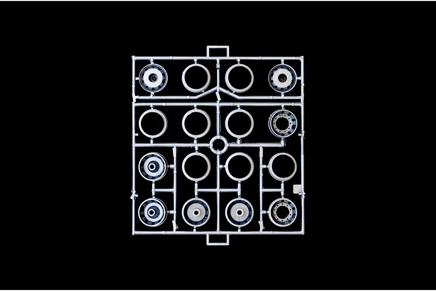 A grey plastic sprue containing various truck wheel and rim components for a 1/24 scale model kit, set against a solid black background.