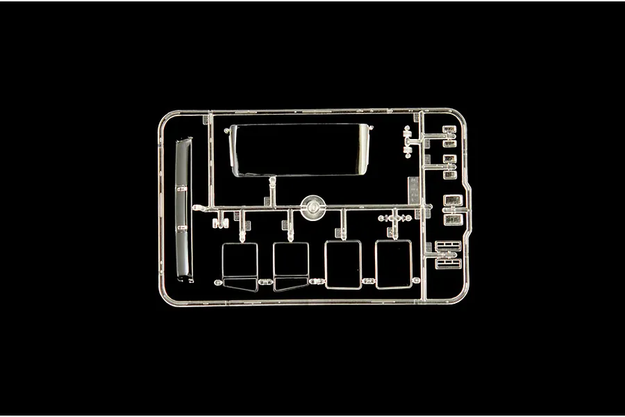 A clear plastic sprue containing various transparent model truck parts, including windows and light lenses, against a black background.