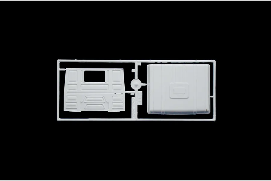 A white plastic model kit sprue containing two truck body panels against a black background.