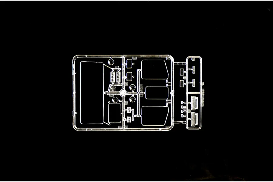 A clear plastic sprue containing various transparent model truck parts, including windows and light lenses, set against a black background.