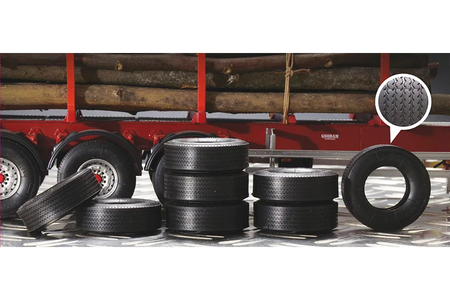 A collection of black rubber scale model trailer tyres arranged in front of a red model log trailer.