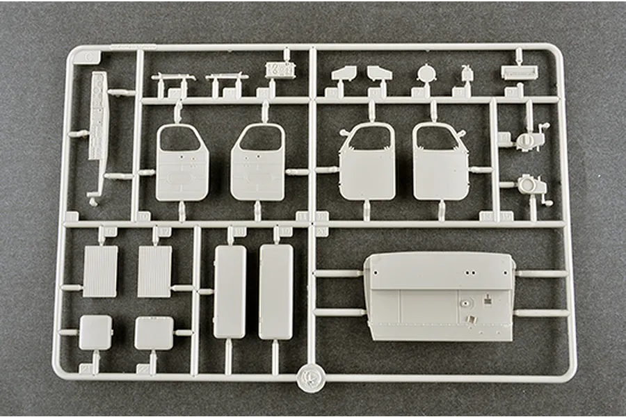 A grey plastic model kit sprue containing various vehicle parts like doors and panels for a 1/35 scale military model.