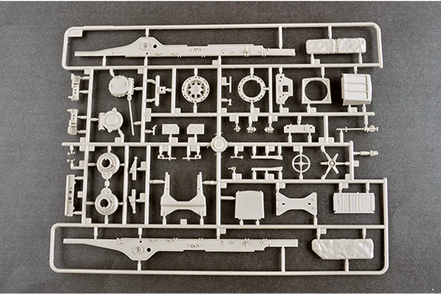 A light grey plastic sprue containing various model parts for a 1/35 scale military vehicle kit, laid out on a dark grey surface.