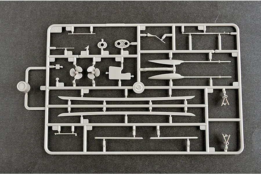 A grey plastic model kit sprue containing various ship parts including propellers, shafts, and structural components on a dark grey background.