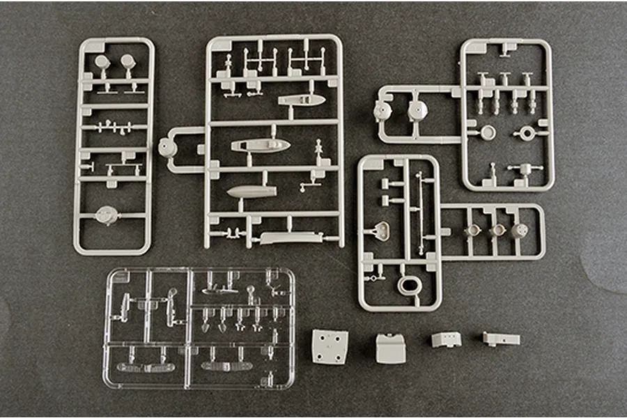Several grey plastic model kit sprues and one clear plastic sprue containing various small ship parts on a dark grey background.