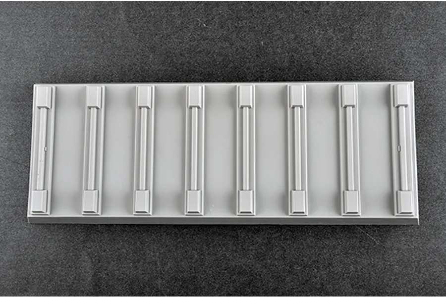 A rectangular grey plastic display stand base for a model kit, featuring eight raised support brackets arranged in a row.