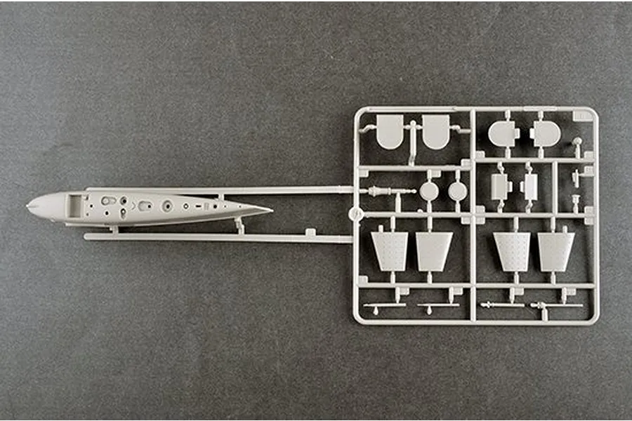 A grey plastic model kit sprue containing parts for a 1/144 scale submarine model, including a hull section and various fins or control surfaces.