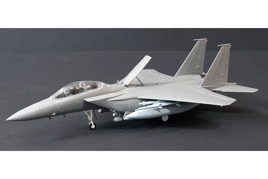 A 1/72 scale plastic model of an F-15K Slam Eagle fighter jet, assembled and unpainted, shown on a dark grey background.