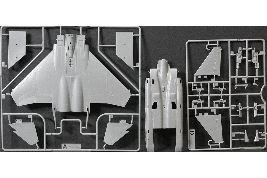 Grey plastic model kit sprues for an F-15 fighter jet, showing main fuselage and wing components on a dark background.