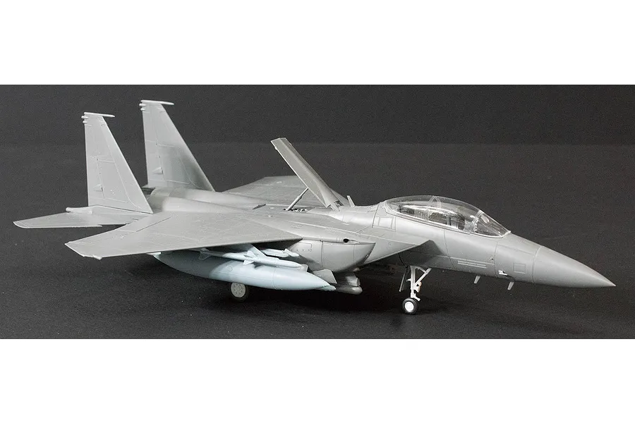 A partially assembled grey plastic model of an F-15K Slam Eagle fighter jet on a dark background.