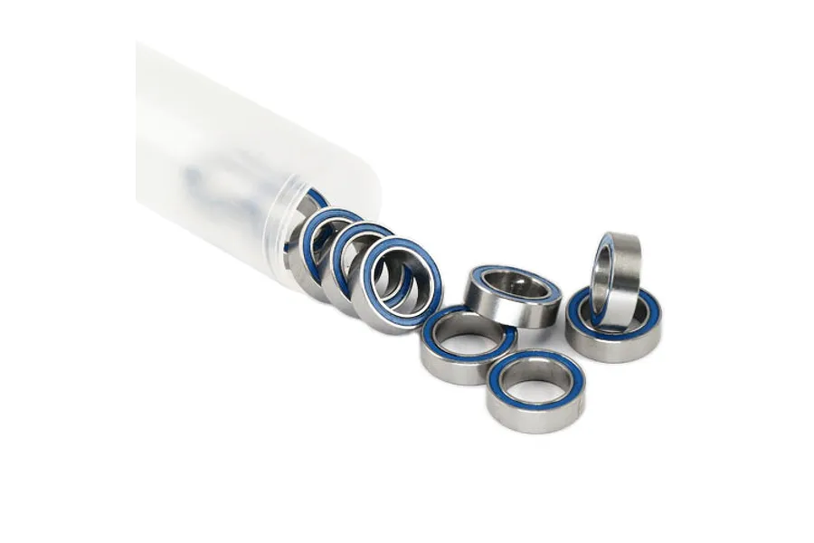 A collection of small metal ball bearings with blue rubber seals spilling out of a translucent plastic storage tube.