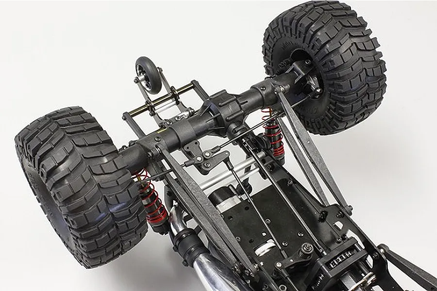 Close-up view of the rear axle and suspension assembly of a Kyosho RC crawler, showing the 4-wheel steering conversion components installed.