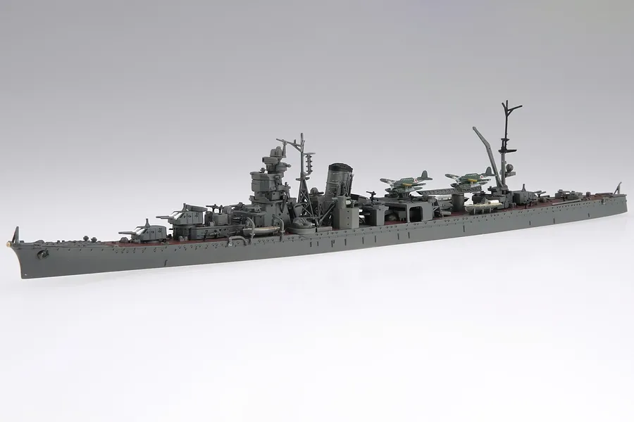 A fully assembled 1/700 scale plastic model of the IJN Sakawa light cruiser, featuring grey hull and deck details with small aircraft on the stern.