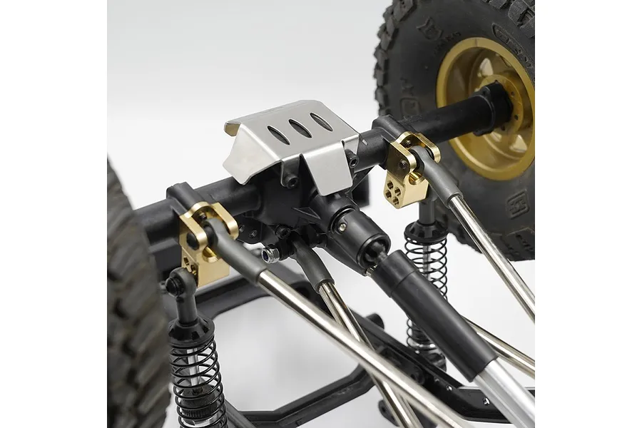 Close-up of an RC crawler rear axle assembly featuring brass suspension link mounts installed on a black chassis.