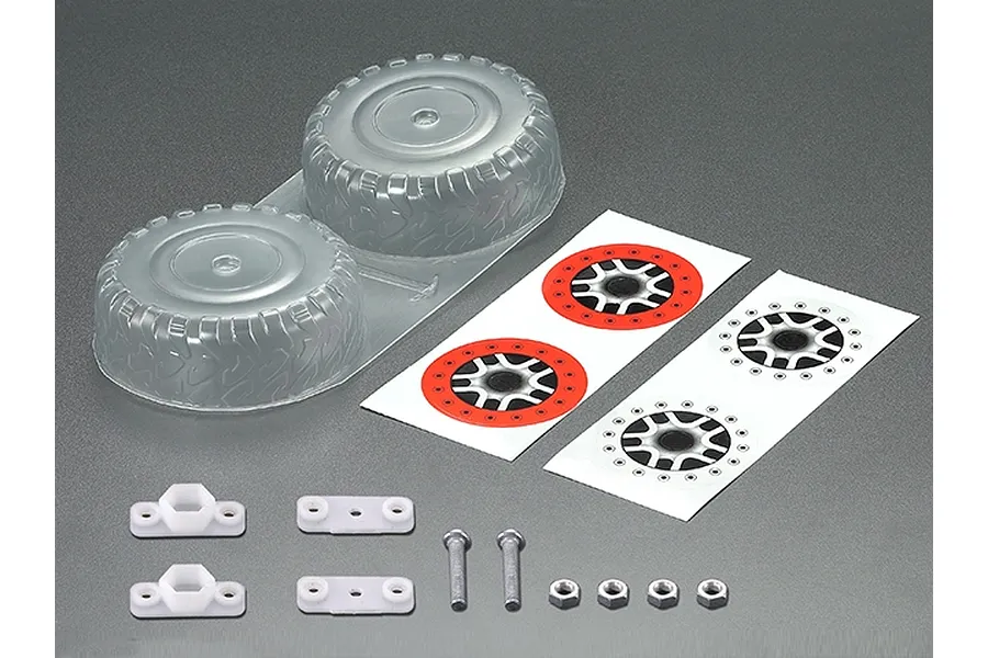 Killerbody 1/10 scale unpainted spare tyre set including two clear plastic tyre shells, decal sheets, white plastic mounts, screws, and nuts.