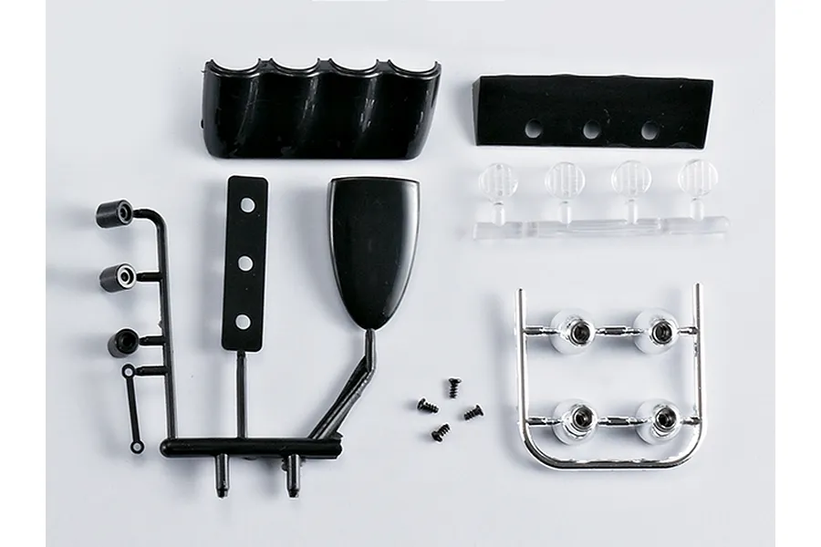 A set of unassembled black and chrome plastic RC car accent light parts including lenses, housing, and small screws on a white background.