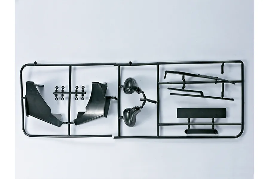 A black plastic parts tree containing various RC car accessories, including side mirrors and trim pieces, on a plain white background.