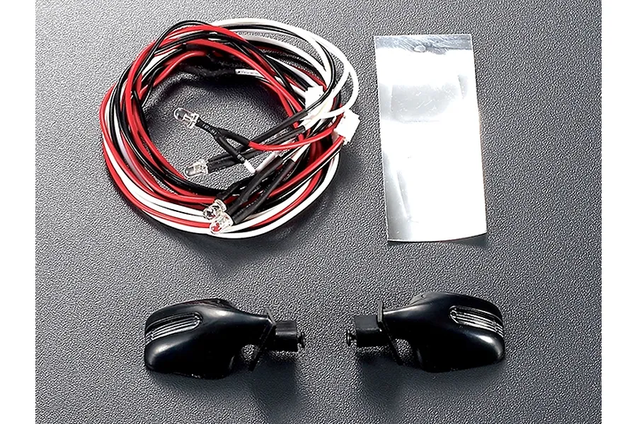 Killerbody 1/10 scale RC wing mirror set with integrated LED light units, wiring harness, and reflective adhesive sheet on a grey surface.