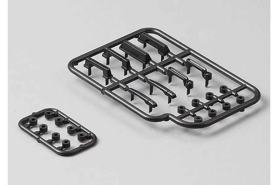 Two black plastic parts trees containing various RC car door handles and small circular components on a light grey background.