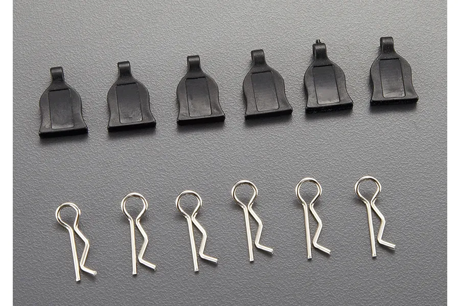A set of six metal RC body clips with black plastic pull tabs arranged on a grey surface.