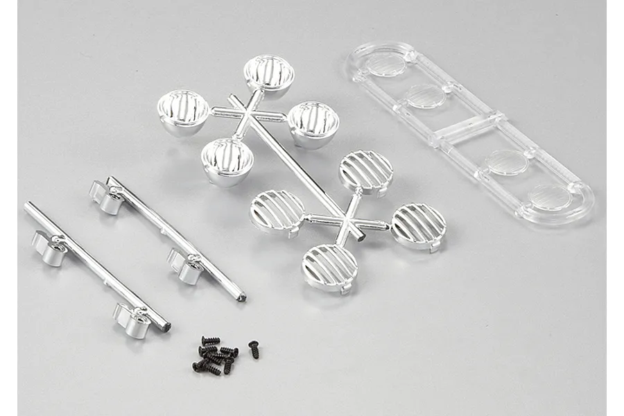 Killerbody 1/10 scale RC truck accent light parts including chrome light buckets, grilles, clear lenses, and small screws on a grey background.