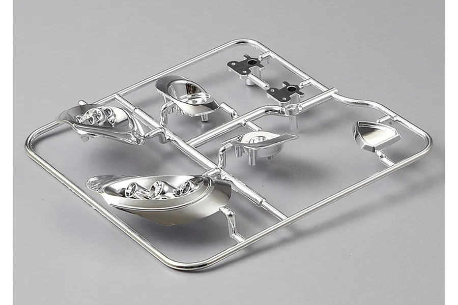 A chrome-plated plastic parts tree for a 1/10 scale RC car model, featuring light buckets and trim components on a grey background.