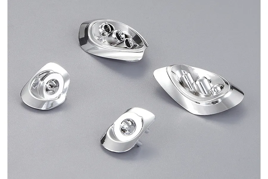 Four chrome-finished plastic light bucket components for a 1/10 scale RC car body, arranged on a grey background.