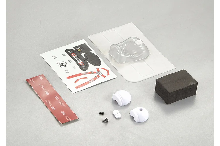 Killerbody driver set components including a clear plastic seat, decal sheet, foam block, double-sided tape, and small plastic parts on a grey background.