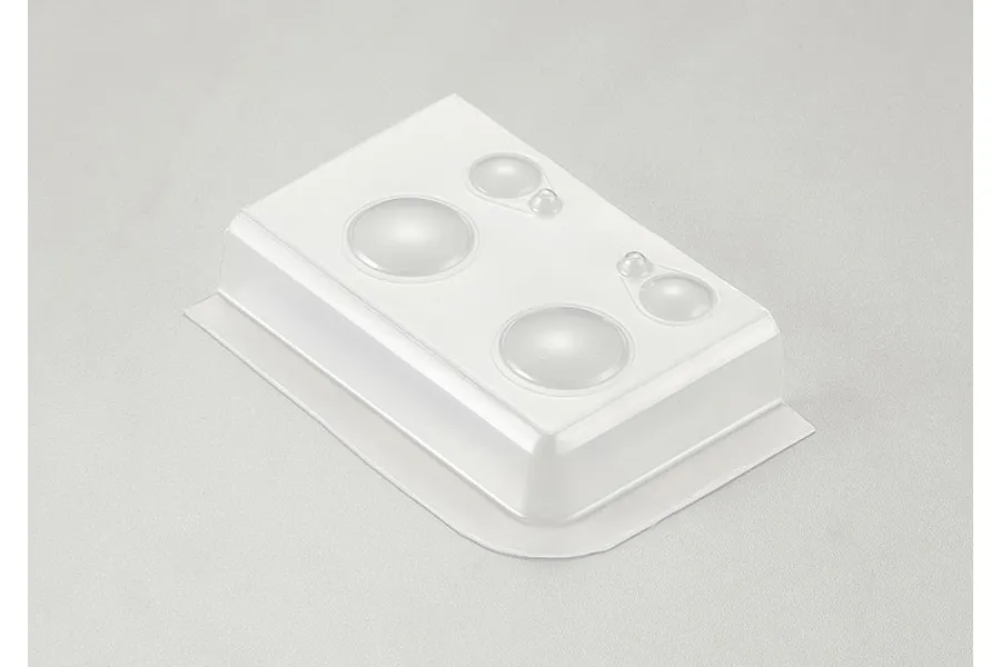 A clear plastic sheet containing molded light lenses for a 1/10 scale RC crawler, set against a plain light grey background.