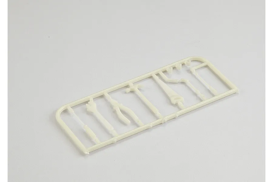 A plastic sprue containing miniature scale model tools including a hammer, saw, and pliers in an off-white color.