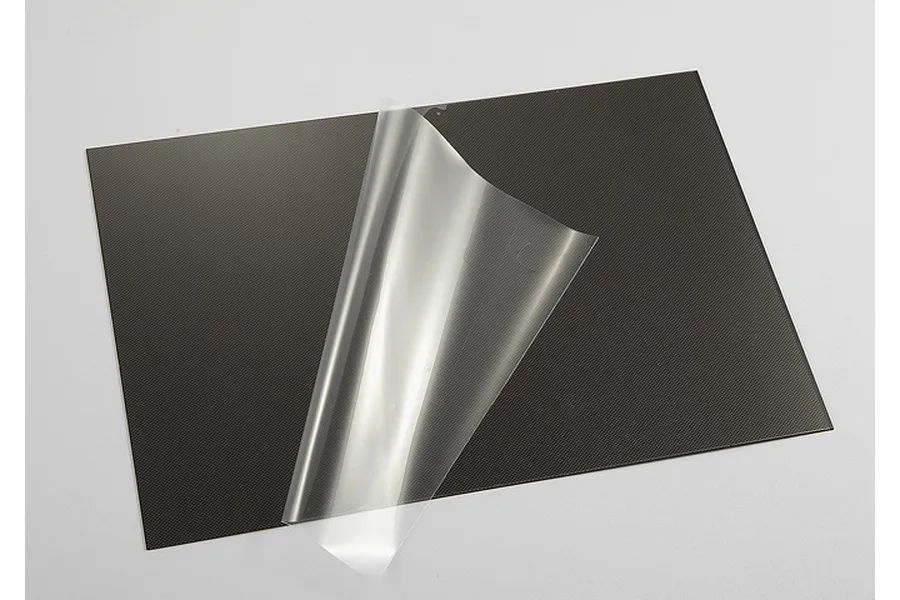 A rectangular sheet with a black carbon fibre pattern, shown with a clear protective film partially peeled back from the surface.