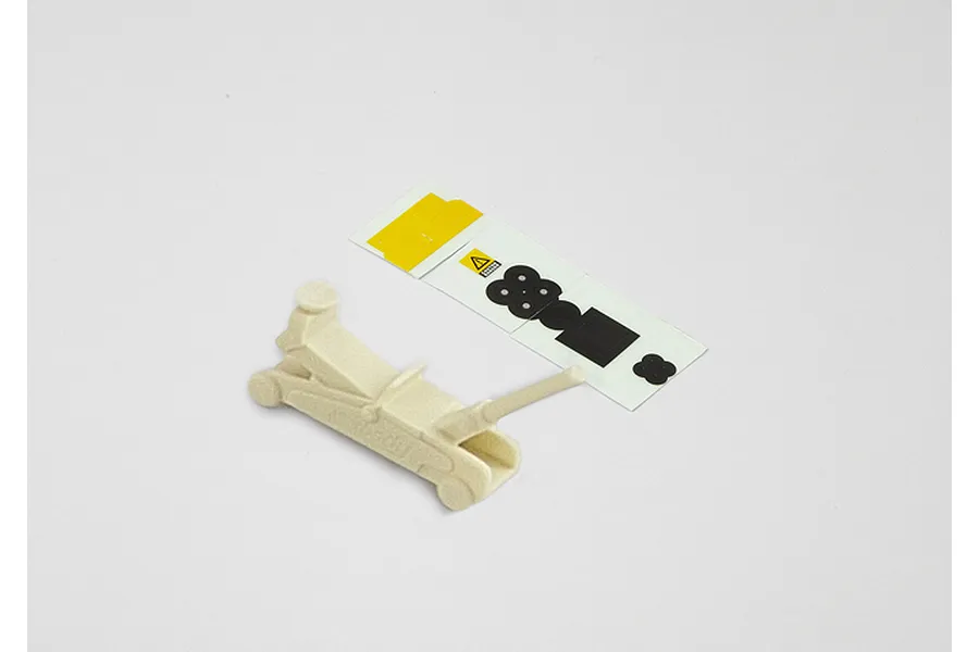 A 1/10 scale unpainted plastic RC lifting jack model with a small sheet of adhesive decals on a white background.