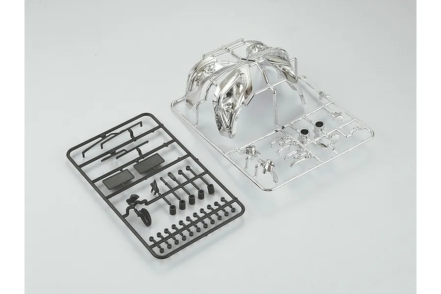 Two plastic model parts trees for a 1/10 scale RC car, one in black plastic and one with a chrome-plated finish, on a plain white background.