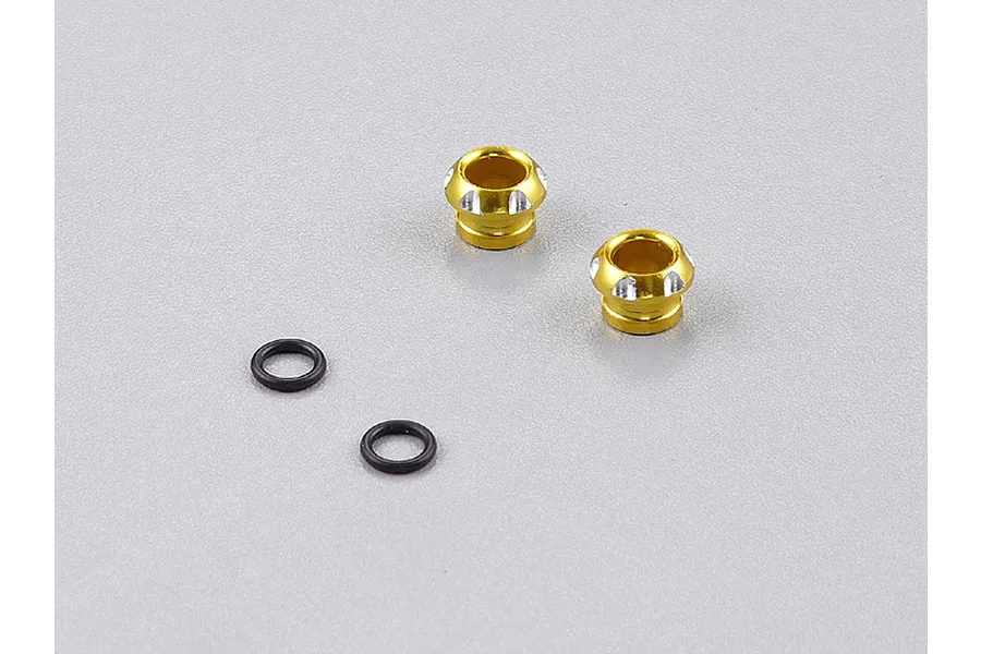 Two gold anodized aluminium 5mm LED light holders and two small black rubber O-rings on a grey surface.