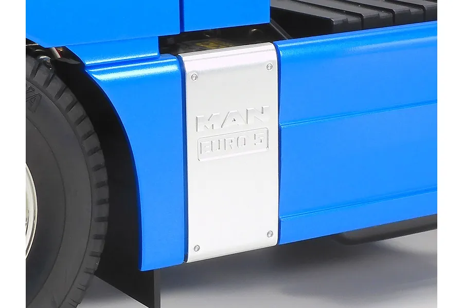 Close-up of the side panel on a Tamiya MAN TGX 26.540 RC truck, featuring a silver MAN Euro 5 emblem against a metallic blue body.