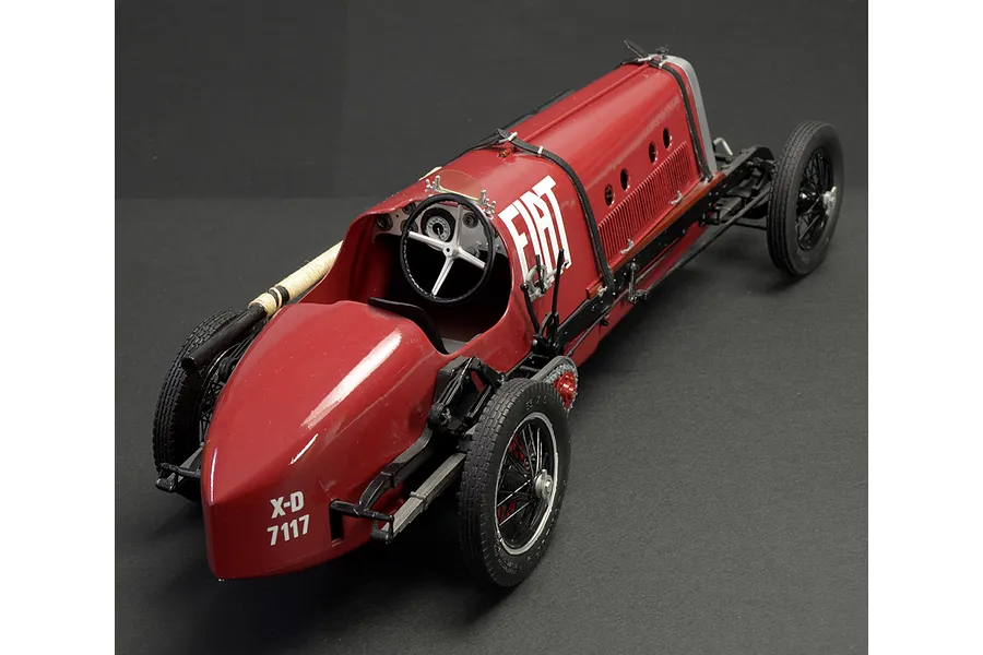 A high-angle studio shot of a 1/12 scale Italeri Fiat Mephistofele model car, featuring a red body, white Fiat branding, and detailed wire wheels.