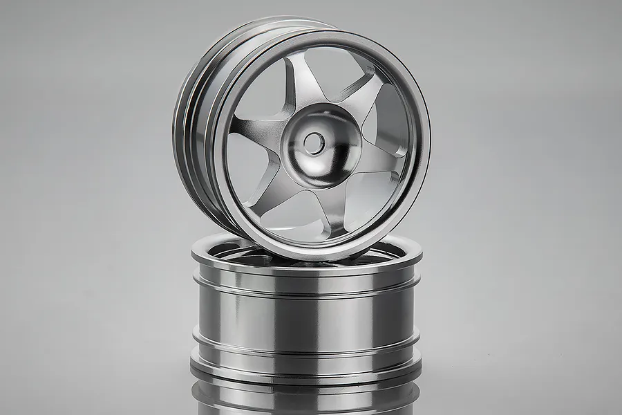 Two silver aluminium 6-spoke RC crawler rims stacked on a reflective grey surface.